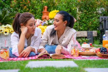 Two women are having picnic in garden.