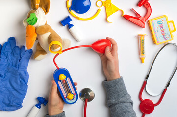 Toy Doctor's Check-Up with Stuffed Animal and Medical Kit on White Background. Pretend Play Doctor Examining Stuffed Bunny with Blue-Gloved Hands.