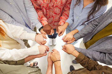 Group of people stands in a circle, holding hands together. Their unity and partnership demonstrate...
