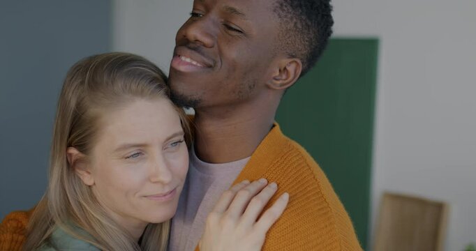 Close-up of loving African American man hugging and kissing Caucasian woman girlfriend expressing love indoors at home. Relationship and love concept.