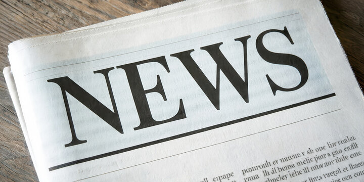 Newspaper with headline news lying on wooden desk as web banner or header