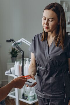 Cosmetologist processes a contactless payment from a client using a card reader