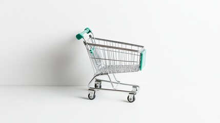 A little, empty metal shopping cart sits all alone against a white backdrop. 
