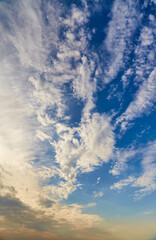 Morning blue sky with wispy clouds and sunlight breaking through a haze, sunrise, vertical shot.