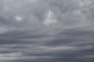 Gray striped clouds cover the sky, overcast weather, gray sky background.
