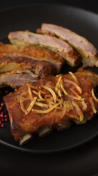 Pork or beef ribs with salt, spices and herbs baked on the grill on a dark concrete background