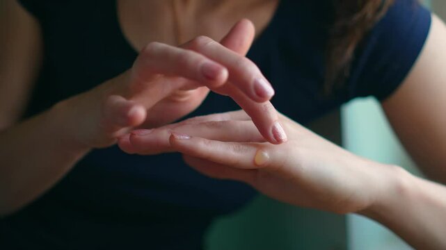 Female with blister on her finger has skin damage while cooking. Woman in kitchen examines burn on her hand from hot oven. Injured skin at home