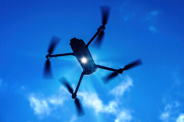 A drone flying against a bright sky, capturing stunning aerial views during a sunny day in an outdoor setting