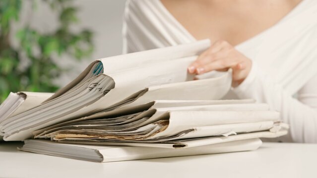 Woman puts on office desk files, sitting and searching through overload stack of folders full of paper documents sheets. Bureaucracy business concept.