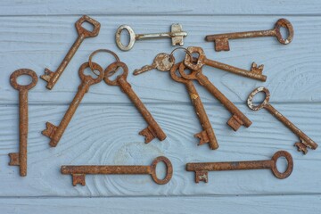 set of old rusty iron  historical different retro brown industrial keys from locks lies on gray wooden table