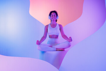 A young African in white sportswear sits in a meditation pose on round platform
