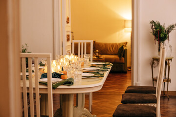 A dining table covered with candles and Christmas decor. Empty cutlery