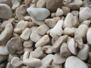 Macro view of gravel beach on the sun. Pebbles on the seaside. Close up of a stone on a sunny summer day.	

