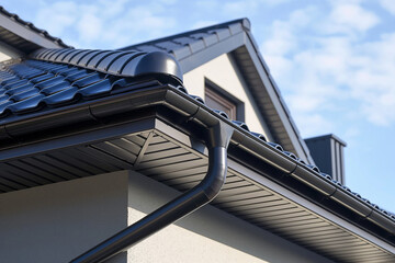 Naklejka premium A black gutter is attached to the roof of a house