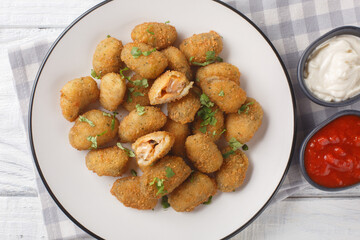 Seafood appetizer breaded mussels served with mayonnaise and ketchup close-up in a plate on a table. Horizontal top view from above