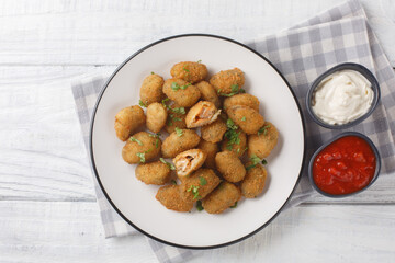 Delicious fresh breaded mussels served with mayonnaise and ketchup close-up in a plate on the table. Horizontal top view from above