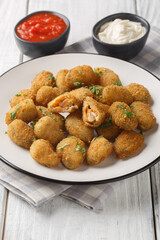 Appetizer Fried breaded mussels served with mayonnaise and ketchup close-up in a plate on the table. Vertical