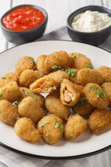 Breaded mussels served with mayonnaise and ketchup close-up in a plate on a table. Vertical