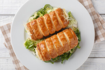 Traditional French Roules au fromage puff pastry tubes with Gruyere cheese and bechamel sauce close-up in a plate on the table. Horizontal top view from above