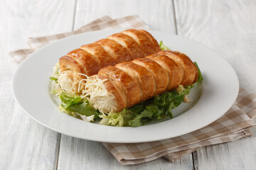 Delicious French puff pastry rolls with gruyere cheese and bechamel sauce close-up in a plate on the table. Horizontal
