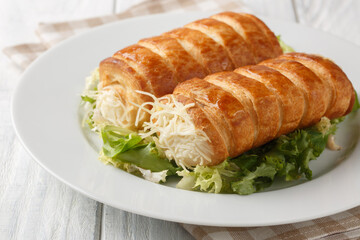 Traditional French Roules au fromage puff pastry tubes with Gruyere cheese and bechamel sauce close-up in a plate on the table. Horizontal