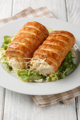 Roules au fromage typical French snack is made of puff pastry rolls filled with a cheesy Bechamel sauce closeup on the plate on the wooden table, Vertical
