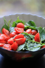 Fresh spinach and tomatoes arranged on a table, perfect for a healthy snack or salad.