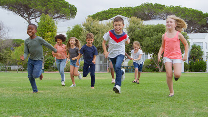 Group Of Children Playing Having Fun Running  Across Park With Friends