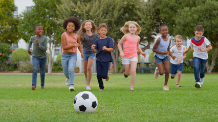 Group Of Children Playing Football With Friends In Park