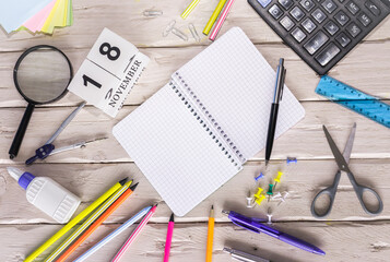 November calendar with number  18. Copy of space note. Top view of blank notepad. Space for text in a checkered sheet, stationery background with accessories.