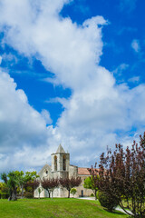 A historic church with a bell tower stands amidst a grassy landscape