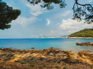 New Moon in the daytime sky over the sea. Landscape with the Moon by the sea coast. Photo of the Earth's satellite.