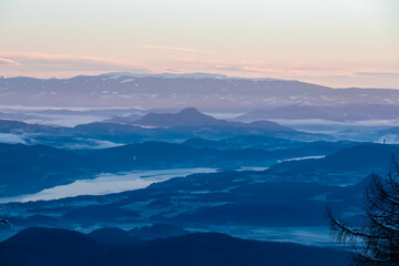 Scenic morning view of Pyramidenkogel in Rosental Valley seen from Karawanks, Carinthia, Austria. Alpine landscape in soft light of dawn. Austrian Alps shrouded in mist. Mystical ethereal atmosphere