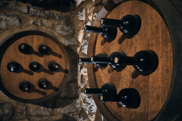 Wine bottles stick out of wooden wine barrells. Wine bottles in a bodega. Wine cellar in a cave