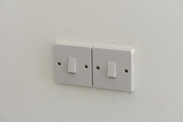 Two White Light Switches Mounted on a Pristine Wall, Ready to Illuminate a Cozy Room at Any Moment