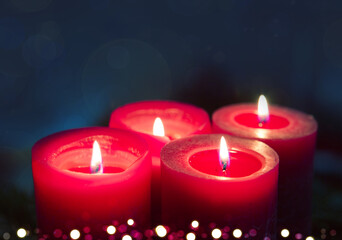 Four burning red Advent candles on black background.