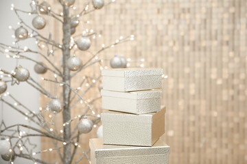 New Year interior decor made of golden boxes, Christmas tree with golden balls against golden wall