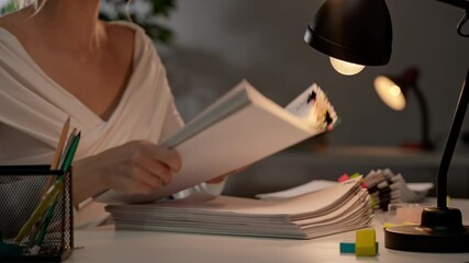 Workaholic woman sitting at office desk sorting organizing overload stack of paper documents with colorful paper clips. Bureaucracy business concept.