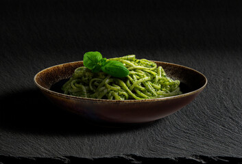 Dark bowl with portion of trenette with Genoese pesto and basil