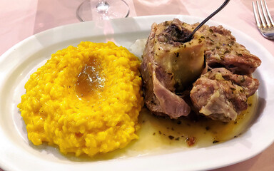 Plate with portion of saffron risotto and Milanese ossobuco