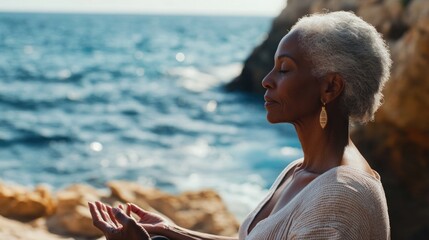 Woman sits cross-legged on beach, eyes closed, hands in prayer position