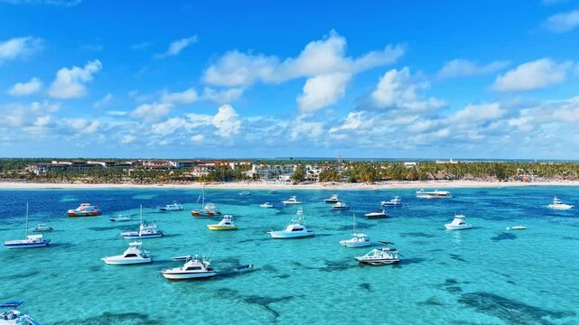 White yachts sailing in the open Caribbean sea with a resort hotel in the background. Leisure, sports and recreation. Sea voyage. Summer holidays in the Dominican Republic.