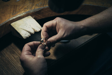 Close-up of a hand of a goldsmith who builds a precious jewel with valuable diamonds. To make the...