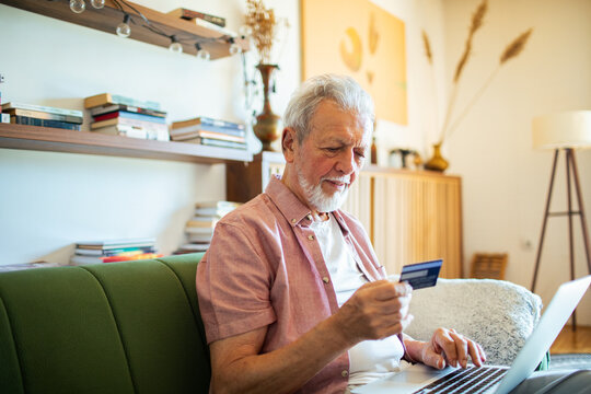 Senior man online shopping with credit card and laptop at home