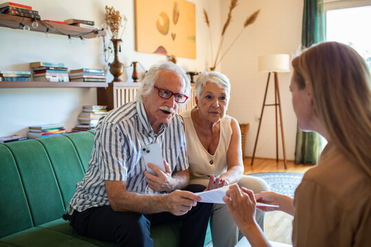 Senior couple receiving financial advice at home from a consultant