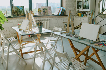 Empty painter workspaces with canvas, aquarelle paints and easel on work table