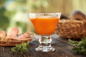 A glass of fresh carrot juice on a table outdoors