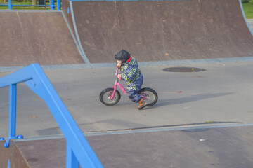 a child, a boy riding a running bike, a bicycle on a sports field, a photo without filters