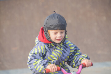 a child, a boy riding a running bike, a bicycle on a sports field, a photo without filters