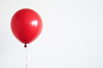 A person grasping a vibrant red balloon high above their head, conveying joy and freedom